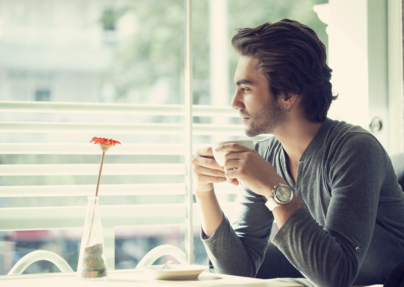 Mees istub akna all üksinda ja joob kohvi